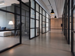 A black framed glass partition system used to create a walkway through a long space.